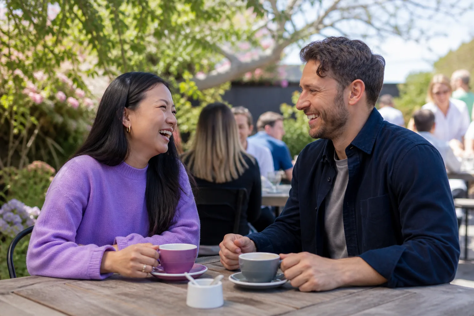Two people talking over coffee at an outdoor table in Jersey